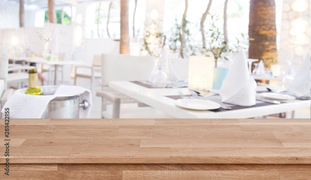 Wooden table top on defocused restaurant background with set tables