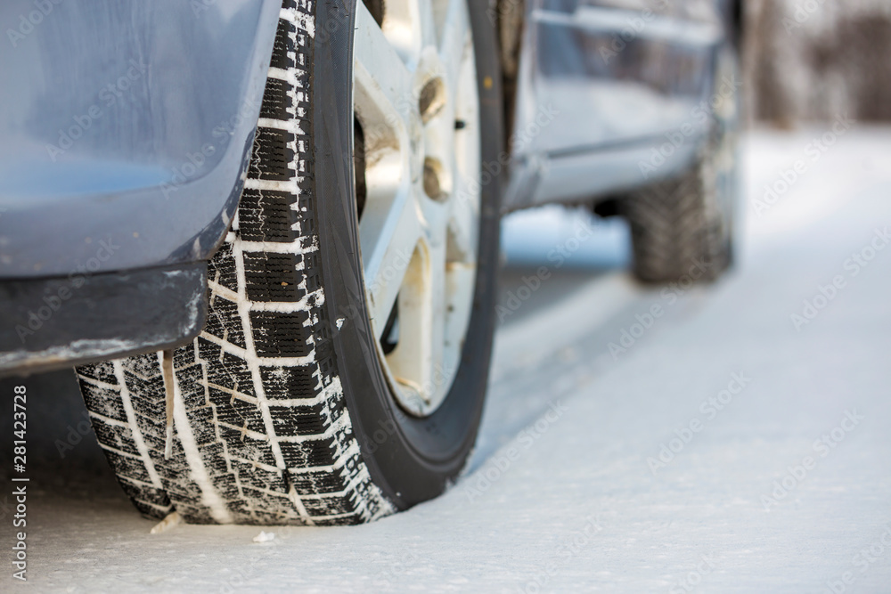 Close-up of car wheels rubber tire in deep snow. Transportation and safety concept.
