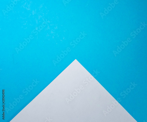 Two colored papers with blue and white flowers. White paper in the form of a triangle on blue. background