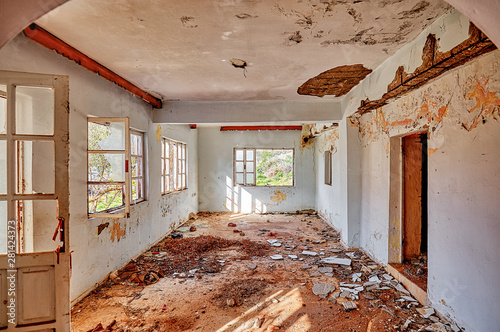 Interior of an old desolated house with white cracked walls and broken windows