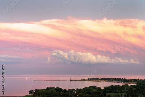 Gorgeous aerial sunset view of calm water of Lake Michigan with pink feathery clouds layered over white fluffy clouds and panoramic view of Montrose and Foster Beach along Lake Shore Drive in Chicago.