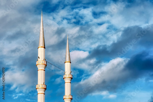 Mosque minaret  loudspeakers and ridge against a vibrant cloudy blue sky background with copyspace