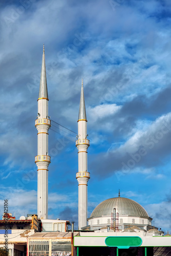 Mosque minaret, dome, loudspeakers and ridge against a vibrant cloudy blue sky background with copyspace