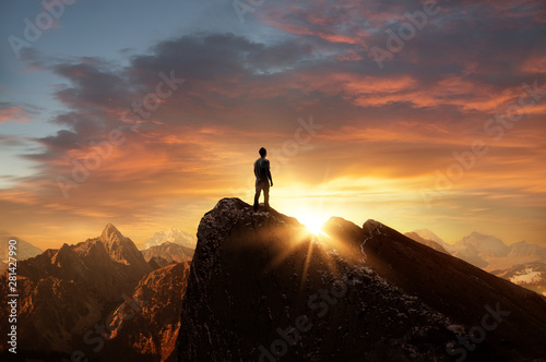 A man standing on top of a mountain as the sun sets. Goals and achievements concept photo composite. photo