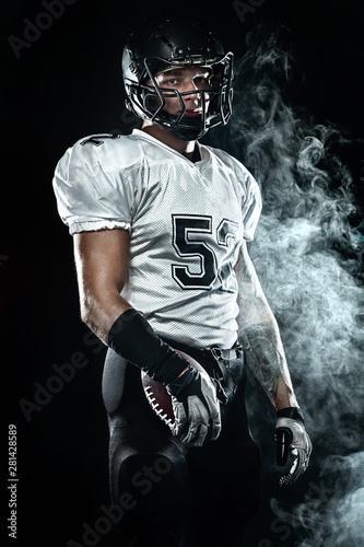 American football sportsman player in helmet on black background with smoke. Sport and motivation wallpaper.