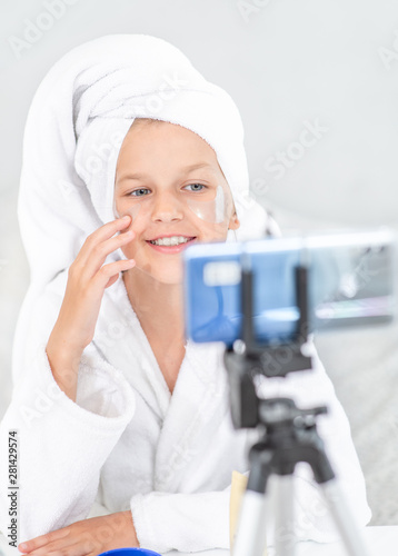 Young happy girl filming the video for her followers about face skin care. Kids blogger concept