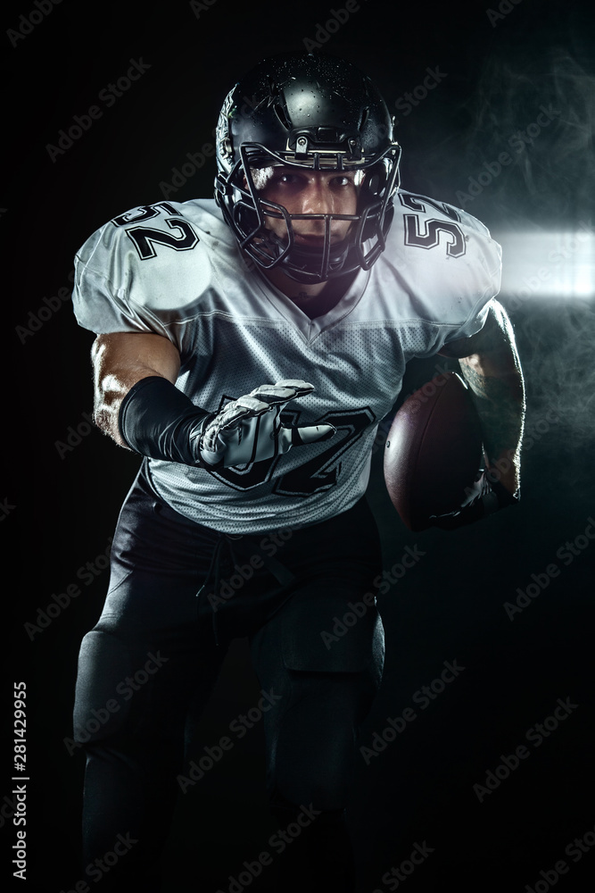 American football player, sportsman in helmet on black background with smoke. Sport and motivation wallpaper.