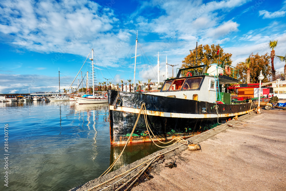 Fototapeta premium Old vintage rusty fishing boat anchored in Turgutreis harbor in Bodrum, Turkey on a bright sunny day.