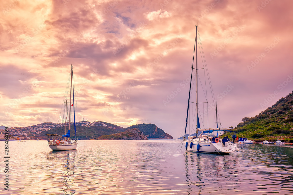 Yachts anchored over the calm sea at sunset in gumusluk bay in Bodrum, Mugla, Turkey. Yachts anchored over the calm sea at sunset in gumusluk bay in Bodrum, Mugla, Turkey.