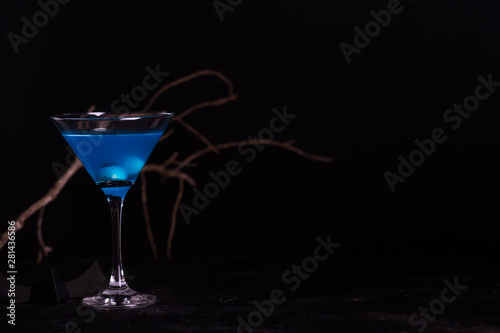 Halloween blue cocktail with artificial eyeballs in a liquid on a black background