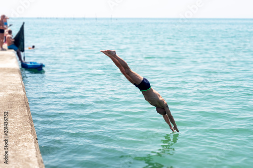 man dives into the sea from a pier