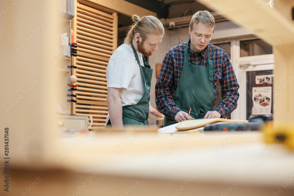 Two masters carpenters are developing the design of a new collection of furniture in their completed woodwork. Concept of professional furniture production Two masters carpenters are developing the design of a new collection of furniture in their completed woodwork. Concept of professional furniture production