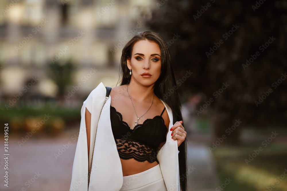 Fototapeta premium beautiful brunette woman with long hair in a white suit and lace top