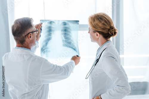 doctor looking at x-ray near colleague in white coat standing in clinic