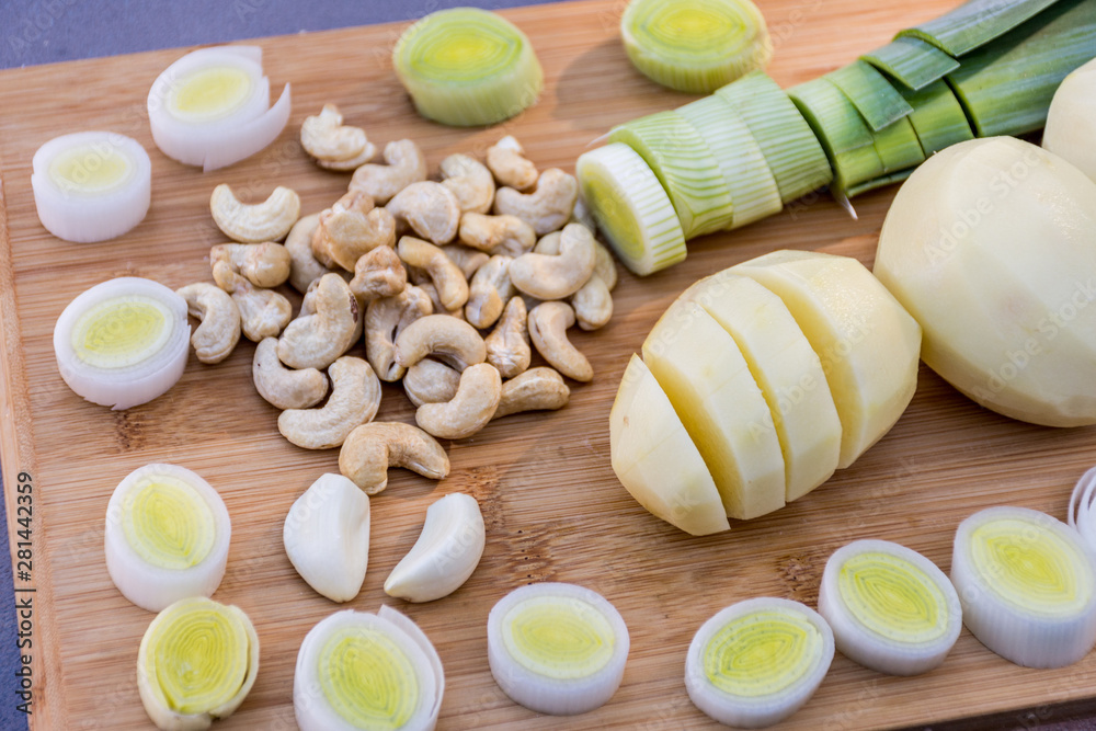 Organic fresh vegetables chopped on a wooden board. Cooking ingredients for a delicious dairy free and gluten free vegan soup - potatoes, leek, cashew and garlic. Recipe Organic fresh vegetables chopped on a wooden board. Cooking ingredients for a delicious dairy free and gluten free vegan soup - potatoes, leek, cashew and garlic. Recipe