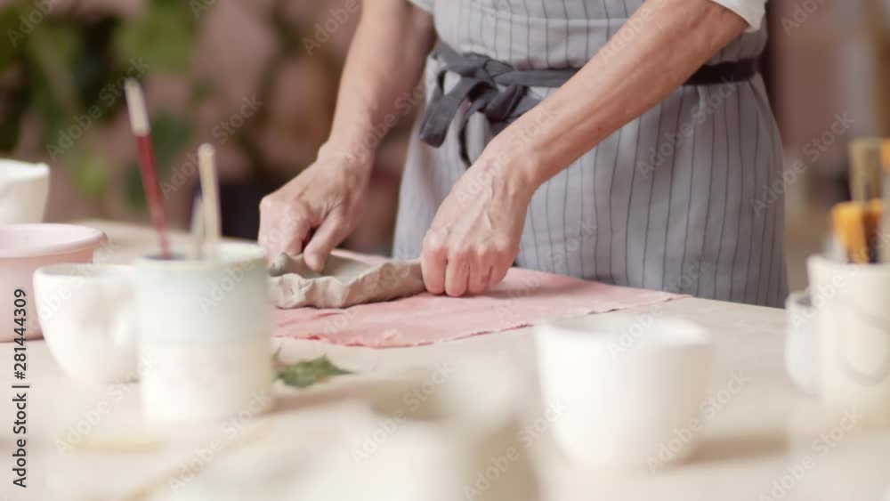 Close up of female hands making plate out of raw clay in ceramic workshop Close up of female hands making plate out of raw clay in ceramic workshop