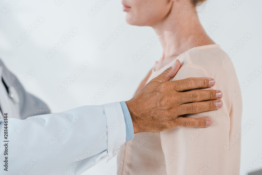 cropped view of doctor touching woman while examining in clinic cropped view of doctor touching woman while examining in clinic
