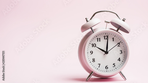 Vintage alarm clock against pink background