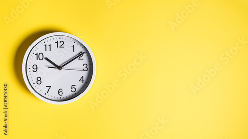 Circular white clock on yellow wall background
