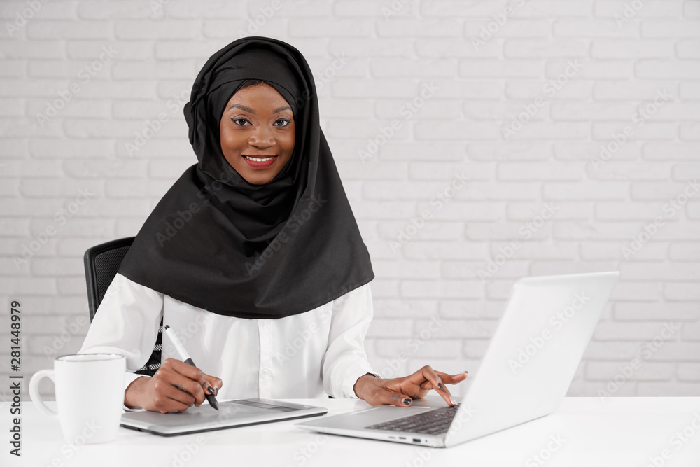 Busy woman in black hijab looking at camera and smiling Busy woman in black hijab looking at camera and smiling