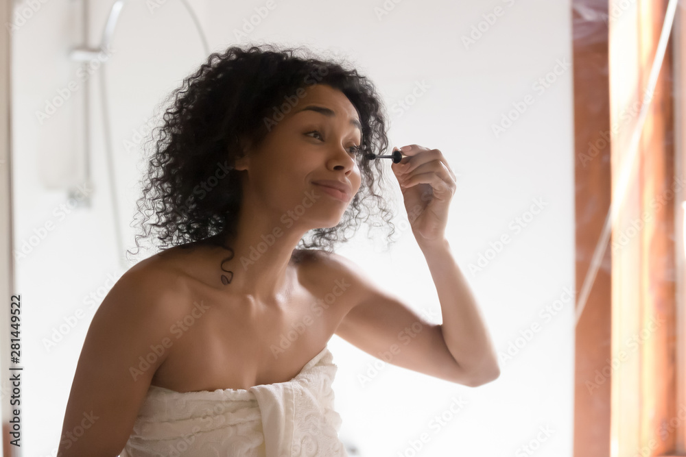 Beautiful mixed race woman looking in mirror applying mascara Beautiful mixed race woman looking in mirror applying mascara