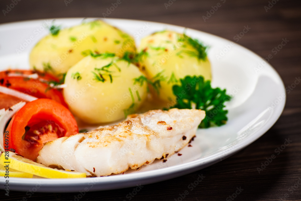 Fried fish with potatoes on wooden table Fried fish with potatoes on wooden table