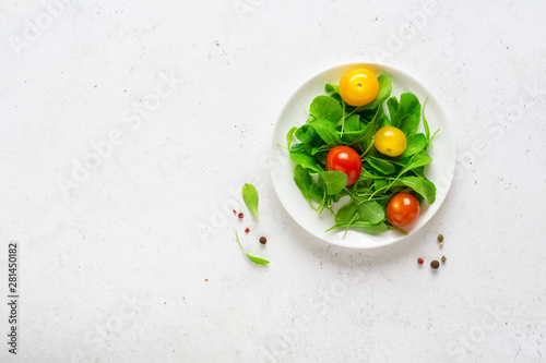 Healthy vegetable salad of fresh arugula and colorful tomatoes. Health care, detox, fitness, diet concept.