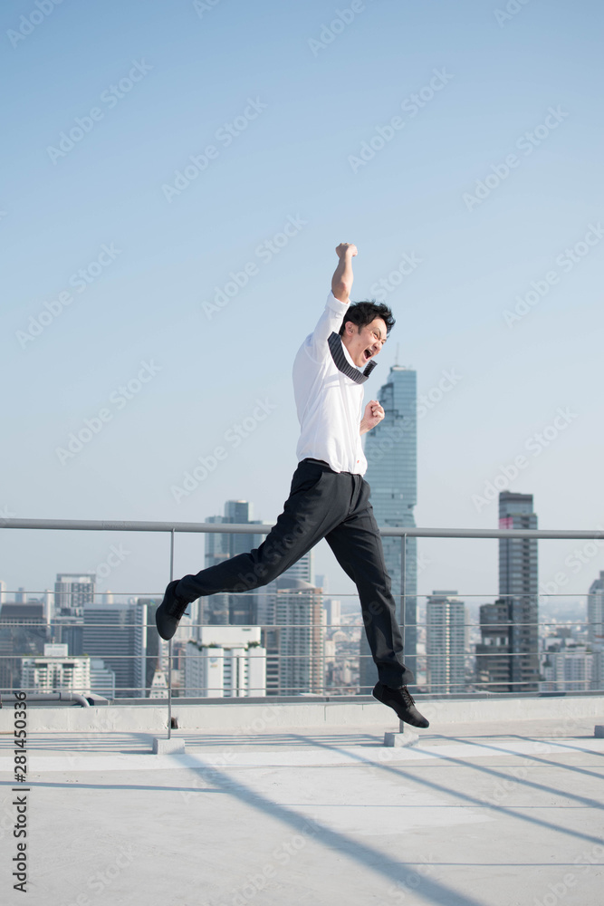 Happy businessman jumping after him work successful on top of building