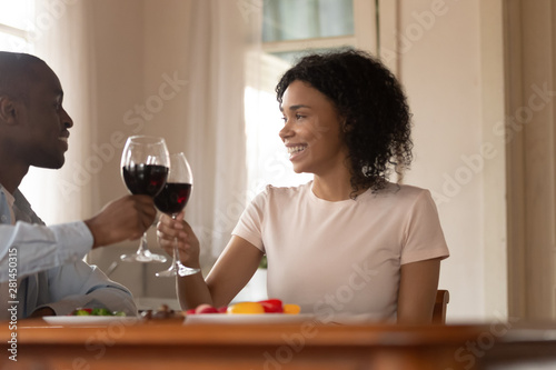 African married couple celebrating clinking glasses toasting holding red wine
