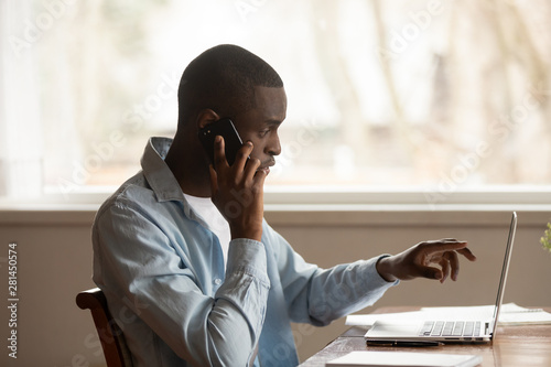 African guy looking at computer screen talk on phone photo