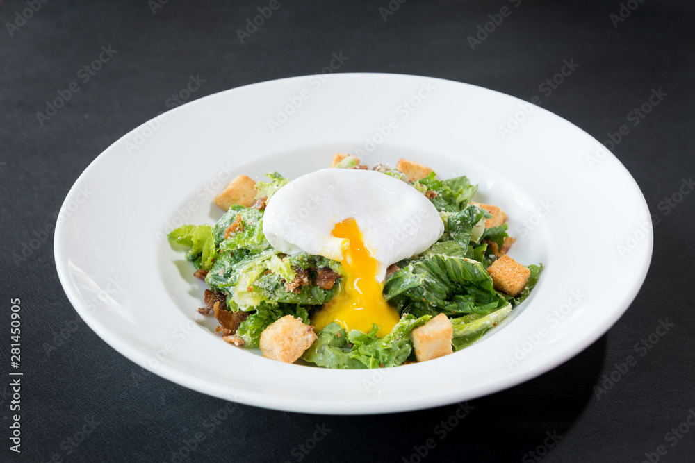 caesar salad with poached egg, mixed vegetable on black textured table caesar salad with poached egg, mixed vegetable on black textured table