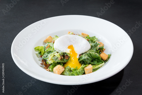 caesar salad with poached egg, mixed vegetable on black textured table