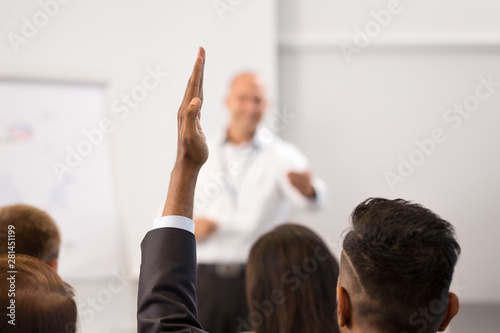 business, education and people concept - businessman raising hand and asking question at conference, presentation or lecture