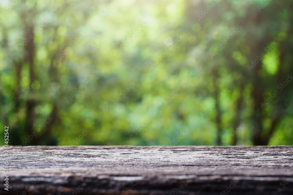 Fototapeta premium old wooden table top on green blurred abstract background from foliage background. Ready used us display or montage products design