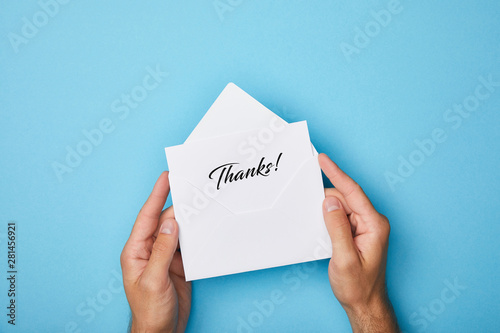Фотография cropped view of man holding envelope and white card with thanks inscription on b
