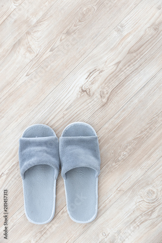 top view of gray wool slipper on brown wooden herringbone floor background texture.