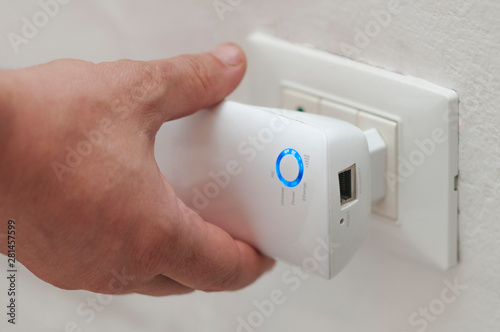 White man insert a wifi repeater in a wall plug photo