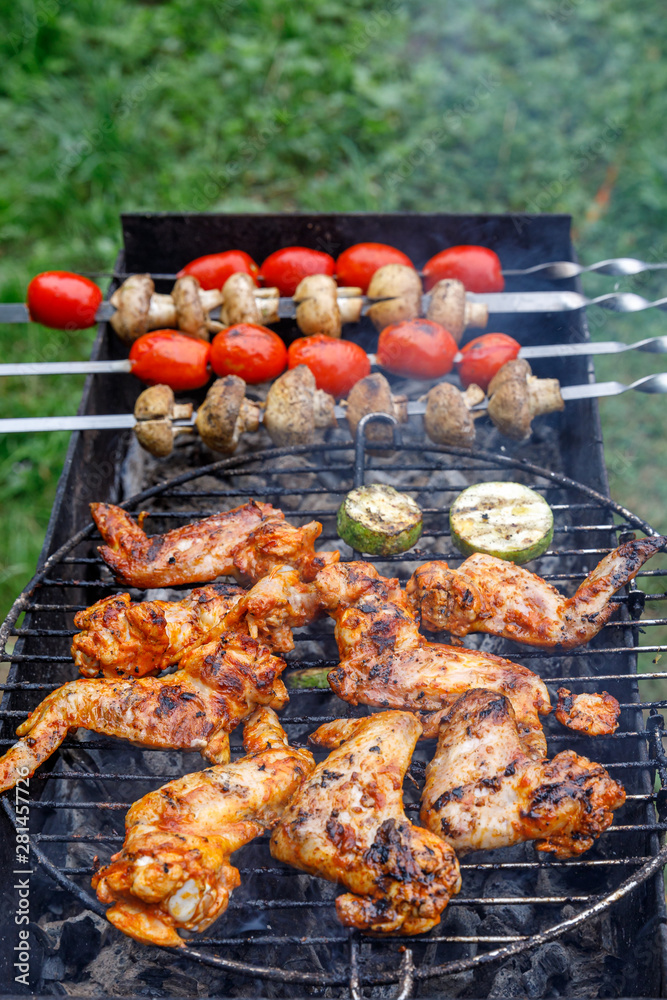Vegetables and grilled chicken wings. tomatoes, mushrooms and zucchini. Chicken on open fire. Summer barbecue party.