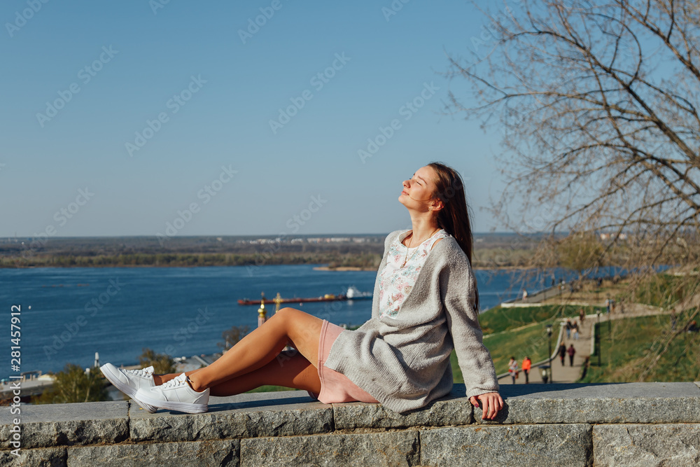 Young beautiful brunette girl walking along the river in Europe. Woman tourist travels to the cities of Europe.