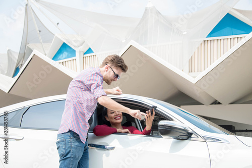 Woman stopping her car and she asked friend about location on her smartphone. photo