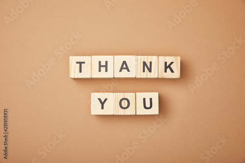 top view of wooden cubes with thank you lettering on beige background