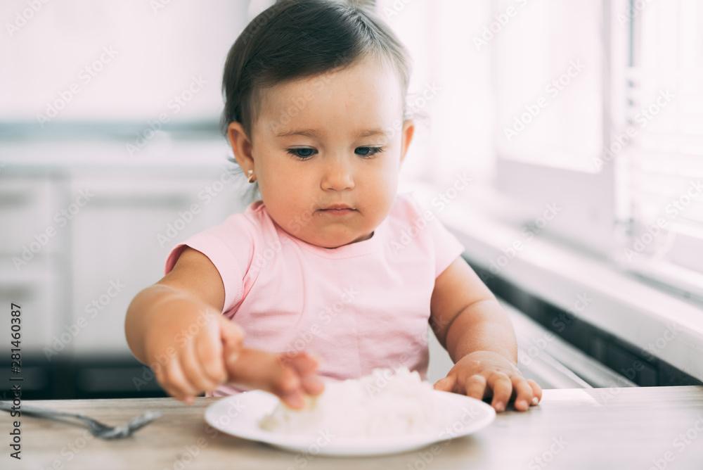 Little baby girl in the kitchen eating sausage and mashed potatoes Little baby girl in the kitchen eating sausage and mashed potatoes