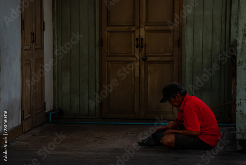 Uncle sitting, fixing his shoes in front of the old room.