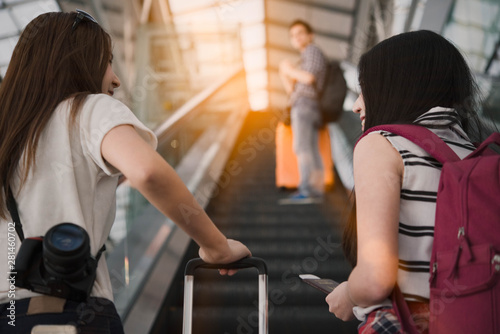 Focus on two young Asian woman traveler with luggage walking to the gate in the airport,Backpacker concept.