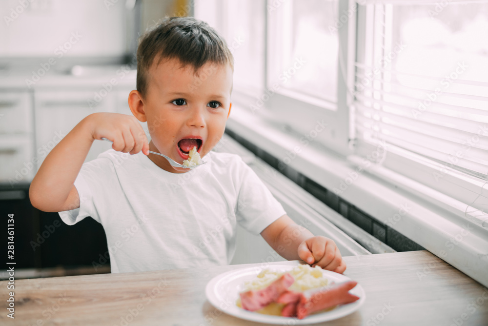 child in the kitchen eating sausage and mashed potatoes child in the kitchen eating sausage and mashed potatoes