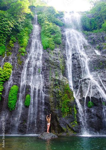 Girl in swimsuit on Waterfall background Banyumala with cascades among the green tropical trees and plants in the North of the island of Bali, Indonesia