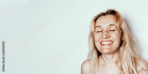 Portrait smiling 40 years old woman with blond hair on light gray background with copyspace