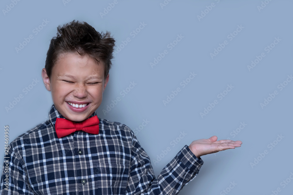 Small boy showing something with palm of hand. Nerdy schoolboy presenting school project portrait. Schoolboy with white smile, preteen child with cupped hand on grey background. Dentistry concept Small boy showing something with palm of hand. Nerdy schoolboy presenting school project portrait. Schoolboy with white smile, preteen child with cupped hand on grey background. Dentistry concept