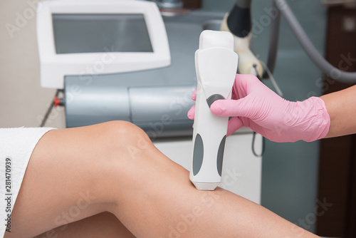 Specialist makes skin tone measurements on a womans leg, to determine the settings for hair laser depilation. First step before depilation. Cosmetology and SPA concept