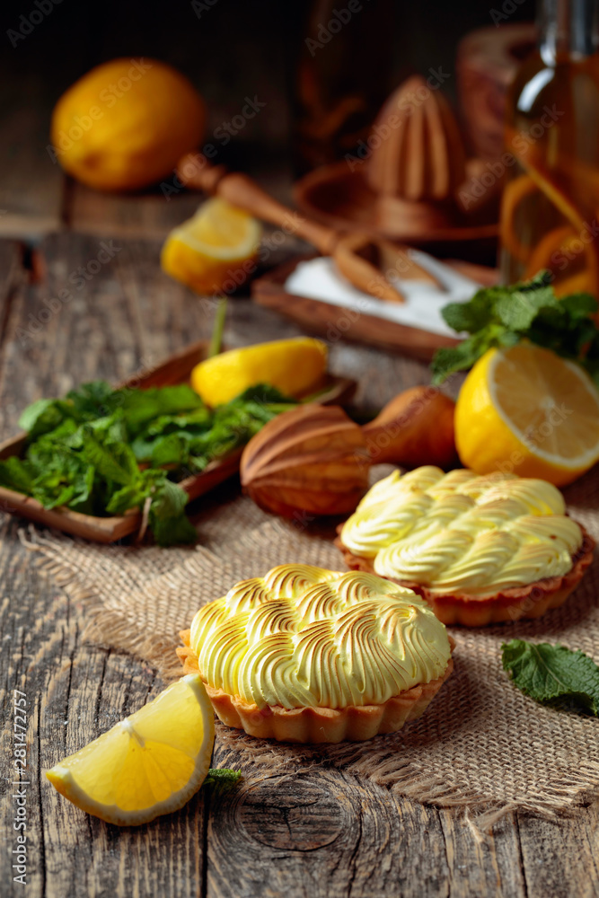 Tartlets with lemon cream and mint on a old wooden table. Tartlets with lemon cream and mint on a old wooden table.